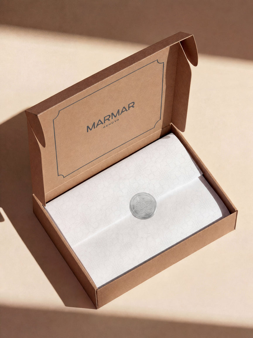 Art of gifting unboxing ritual for MarMar Genova, with monogram tissue paper, monogram silver sticker and blue paper confetti.